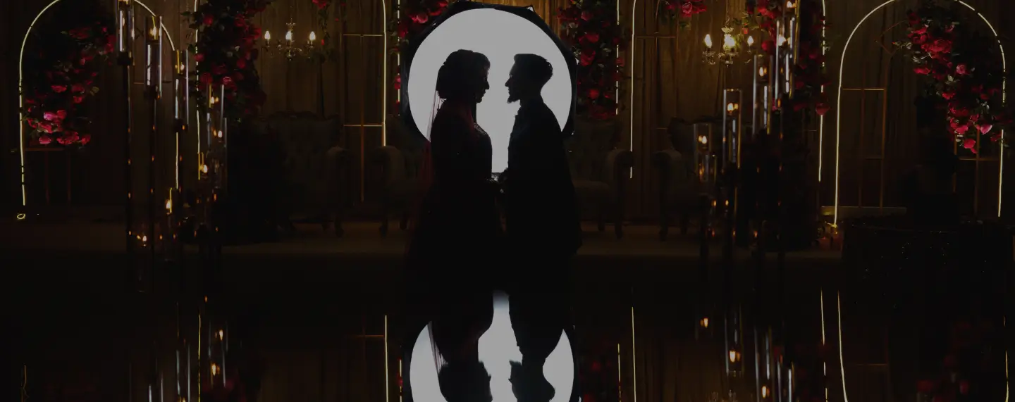 Bride and groom silhouetted beneath a chandelier at Meridian Grand — luxury wedding venue London.