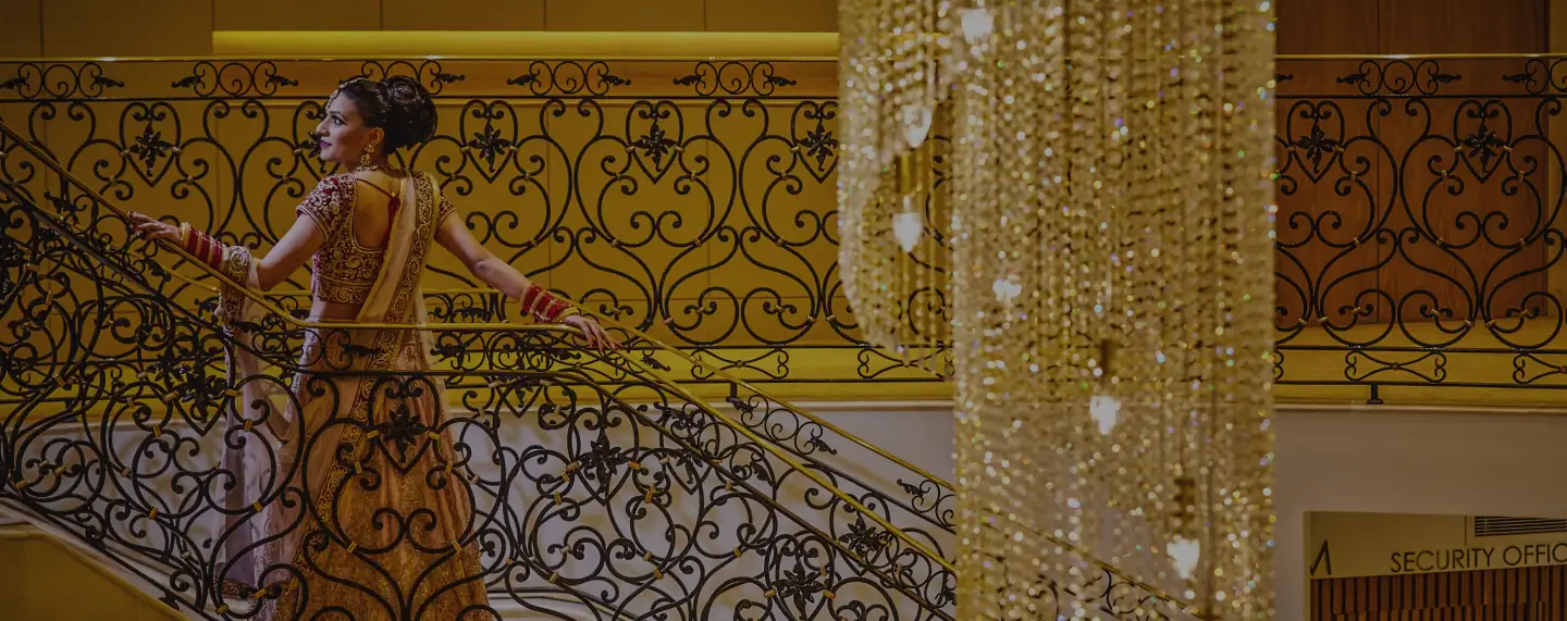 Bride in traditional dress on an ornate staircase at Meridian Grand — Sikh wedding venue London.