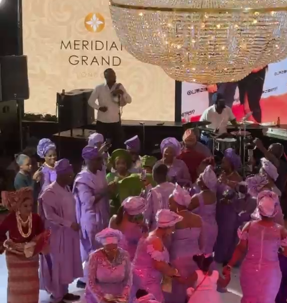 Wedding guests in matching lilac aso ebi and gele on the ballroom floor at a Nigerian wedding at Meridian Grand