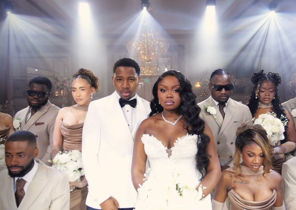 Bride, groom and bridal party posed beneath a crystal chandelier and stage spotlights in a ballroom at Meridian Grand